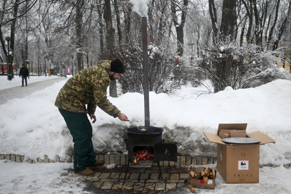 Một tình nguyện viên đang rán bánh trên bếp lò tại một điểm trợ giúp tại công viên ở Kiev